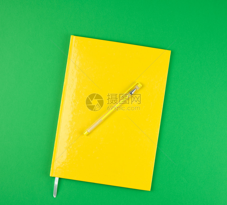 绿色背景顶视图上的黄色关闭笔记本和黄色图片