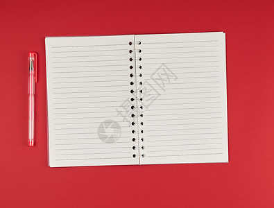 在红背景顶视图空白纸上打开线和凝胶笔的记本图片