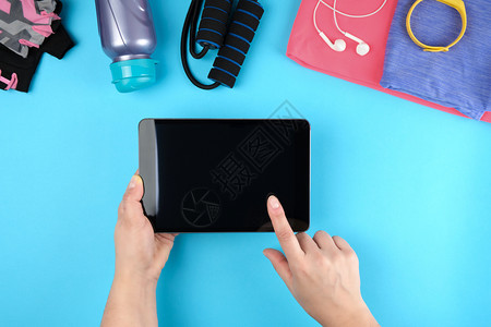 女手握电子平板空白黑屏旁边是健身衣蓝背景顶视图背景图片
