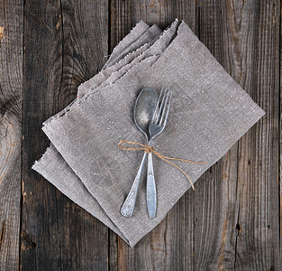 旧金属叉子和勺用褐绳捆绑在灰色纸巾上仪器被跨越图片