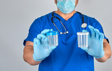 手灰穿蓝色制服和乳胶手套的医生携带一个空塑料容器用于抽取灰底尿液样本背景