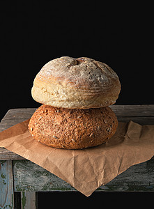 两大面包放在棕纸上黑色背景图片