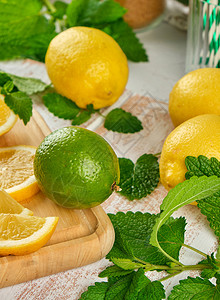 成熟的黄柠檬和石灰白木板上的薄绿色柠檬或莫吉托的成分图片
