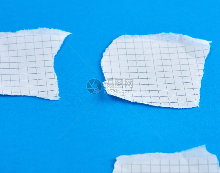 在蓝色背景下方形的白纸撕裂边缘白纸片关闭图片