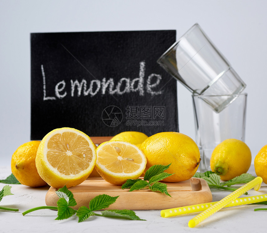 新鲜成熟的全黄色柠檬和黑色框架上面写着柠檬水是制作饮料的原料灰色背景图片