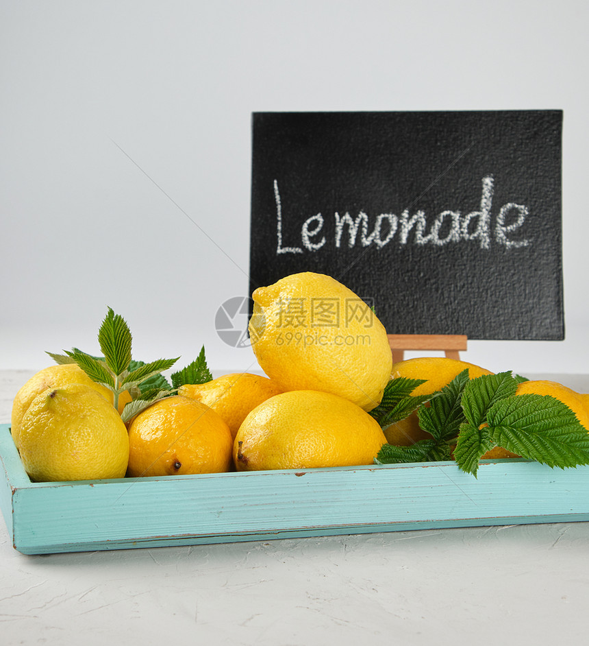 新鲜成熟的全黄柠檬和黑框含水饮料的原图片