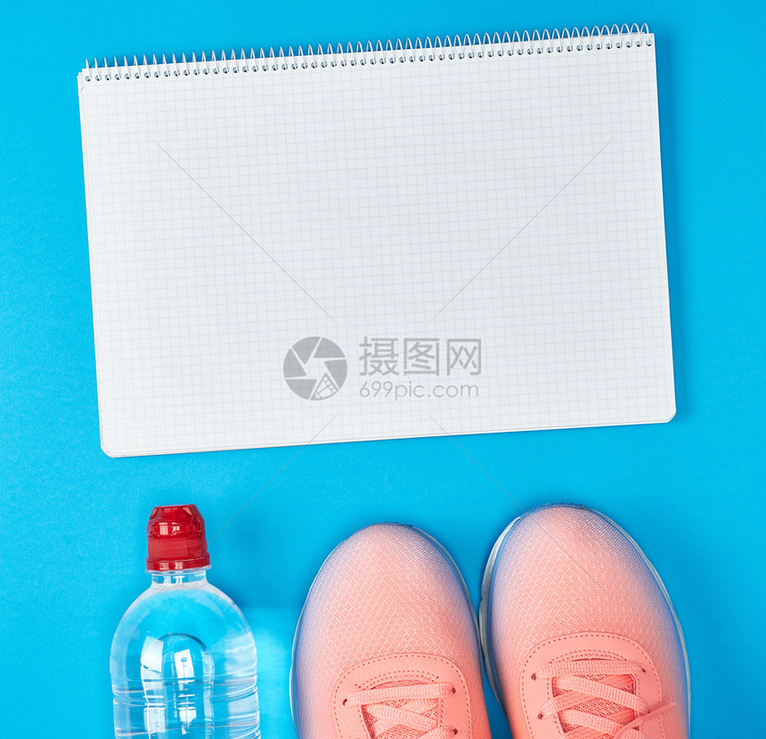 开放的空笔记本和运动妇女健身服装顶视蓝背景图片