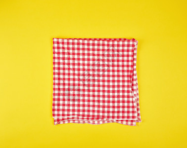 在一个黄色背景的笼中折叠成红色的厨房毛巾图片