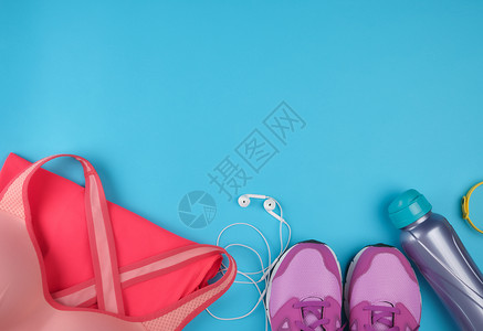 粉红妇女运动鞋瓶水衣服和胸罩用于蓝色背景顶视复制空间的运动图片