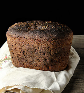 烤黑麦面包粉在毛巾上木制旧桌子黑色背景图片