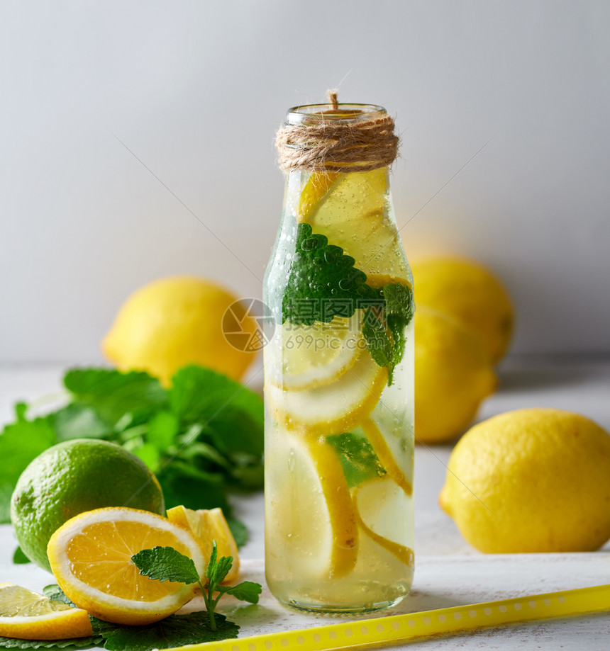 柠檬汁加薄荷叶玻璃瓶中的石灰与鸡尾酒的原料相邻图片