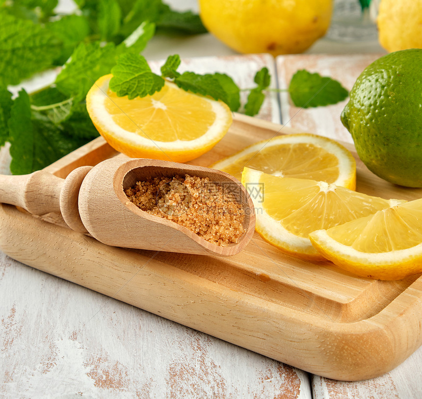 成熟的黄柠檬和褐糖白木板上一串新鲜薄荷柠檬汁的原料图片