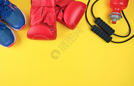 红色拳击手套和蓝运动鞋顶视黄色运动背景图片