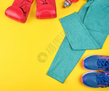 一对蓝色运动鞋红皮拳击手套和绿色衣服黄运动背景图片