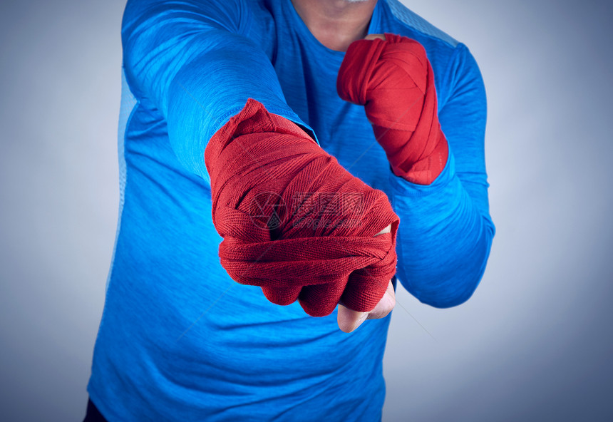 身着蓝礼服的运动员站在战斗运动的进攻姿势上双手臂红色绷带右前针图片
