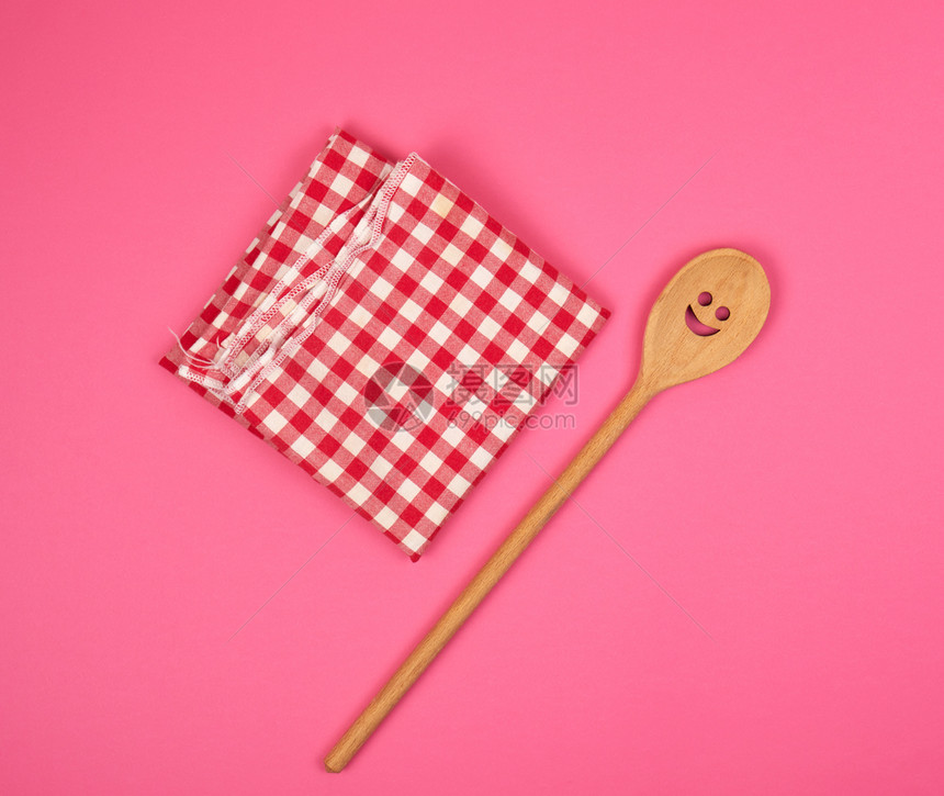 红厨房毛巾上刻面的木勺子粉红色背景复制空间图片