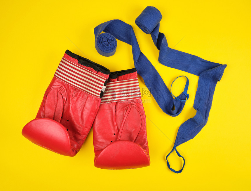 一对红色皮革拳击手套和蓝纺织品绷带黄色平面图片