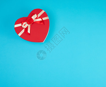 红礼物盒以心脏形式在蓝背景上鞠躬复制空间图片