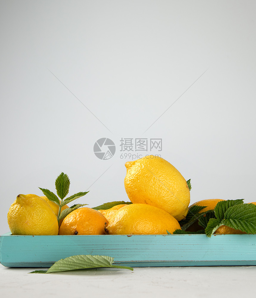 蓝木板上新鲜的黄柠檬用于制造夏季饮料的原复制空间图片