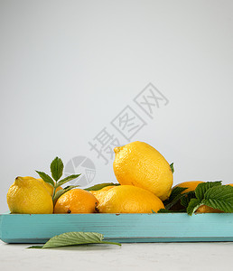 蓝木板上新鲜的黄柠檬用于制造夏季饮料的原复制空间图片