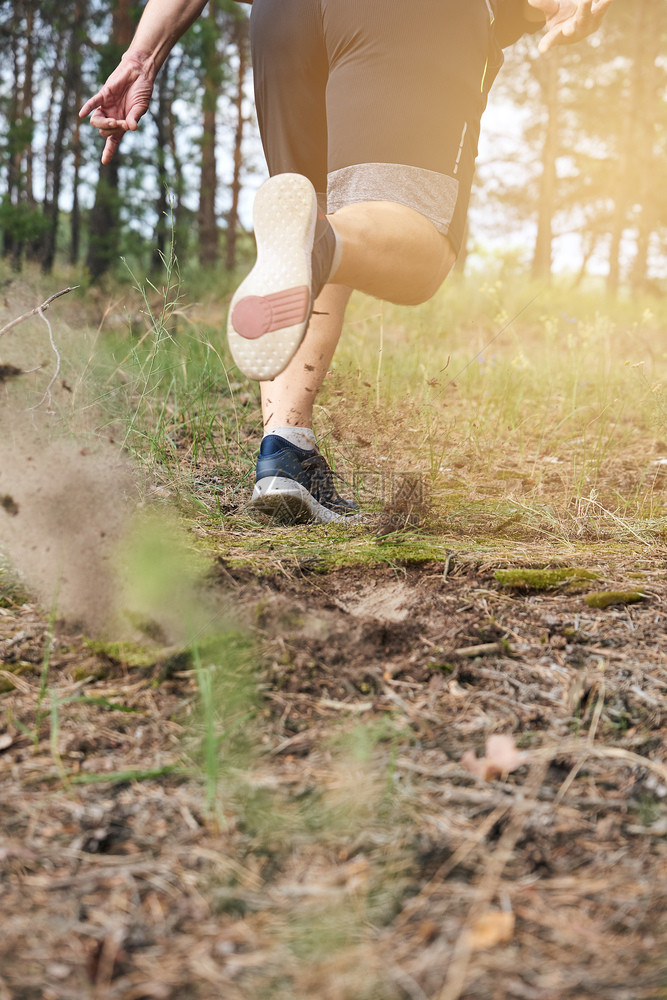 身穿黑短裤的成年男子奔跑在迷幻的森林中对抗明亮的阳光健康生活方式的概念和在新鲜空气中奔跑图片