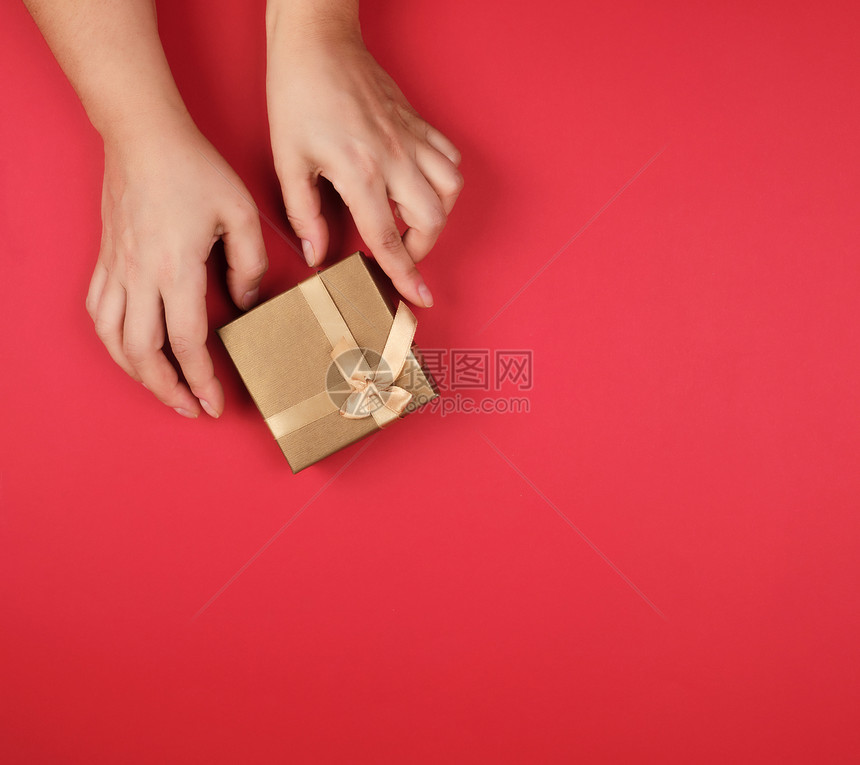 两手握着一张纸封的金盒红色背景喜庆图片