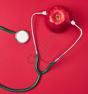 红背景保健概念的开苹果和绿色医学听诊器背景图片