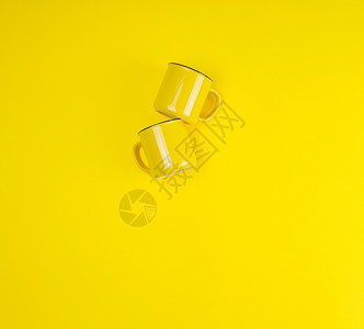 两个黄色陶瓷杯手柄在黄色背景平底复制空间上图片