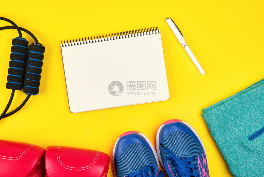 开放的空笔记本和运动妇女健身服装顶视黄色背景平铺图片