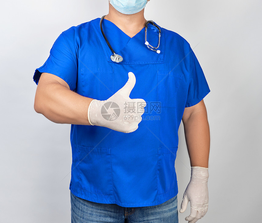 穿蓝色制服和乳胶白手套的男医生显示右手势就像拇指举起图片