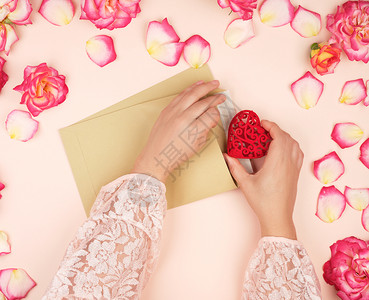 两只女手把红心放在棕色纸包里祝贺节日与爱的概念图片