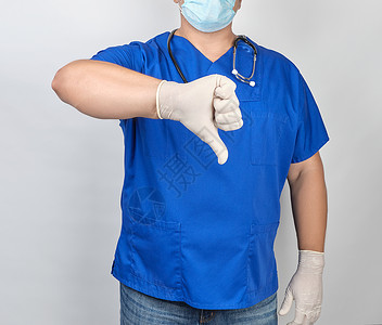 蓝色制服和白乳胶消毒手套的医生穿蓝色制服和白乳胶消毒手套显示一种势是不好或喜欢一种对某事评价不当的概念背景图片
