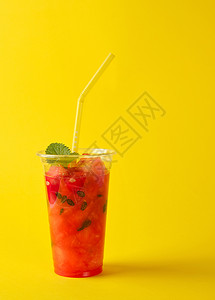 红色西瓜的冰雪放在塑料杯里紧闭黄色背景图片