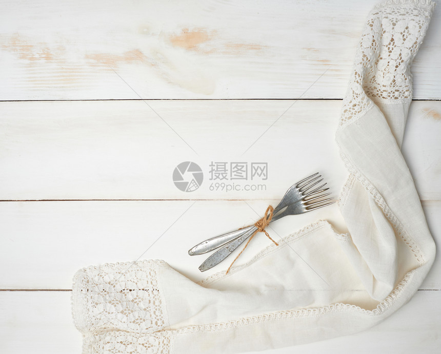 白色木质背景的两根用绳子钉起来的铝叉紧靠棉毛巾顶端的视野图片