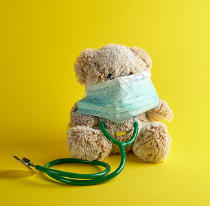 灰色泰迪熊和黄背景的绿医学听诊器儿童治疗概念图片