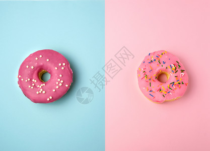 粉红色圆甜圈有彩色喷洒位于蓝粉背景顶层视图糊面颜色上图片