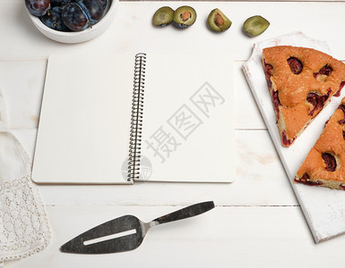 白页的开放笔记本有李子和新鲜水果的烤馅饼顶视图平铺图片