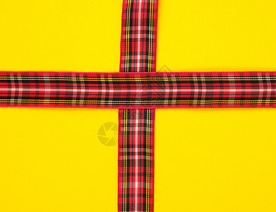 在黄背景节日的上用盒式装饰的红色丝带图片