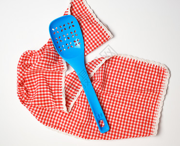 蓝塑料厨房勺子躺在红色白厨房毛巾上顶视图片