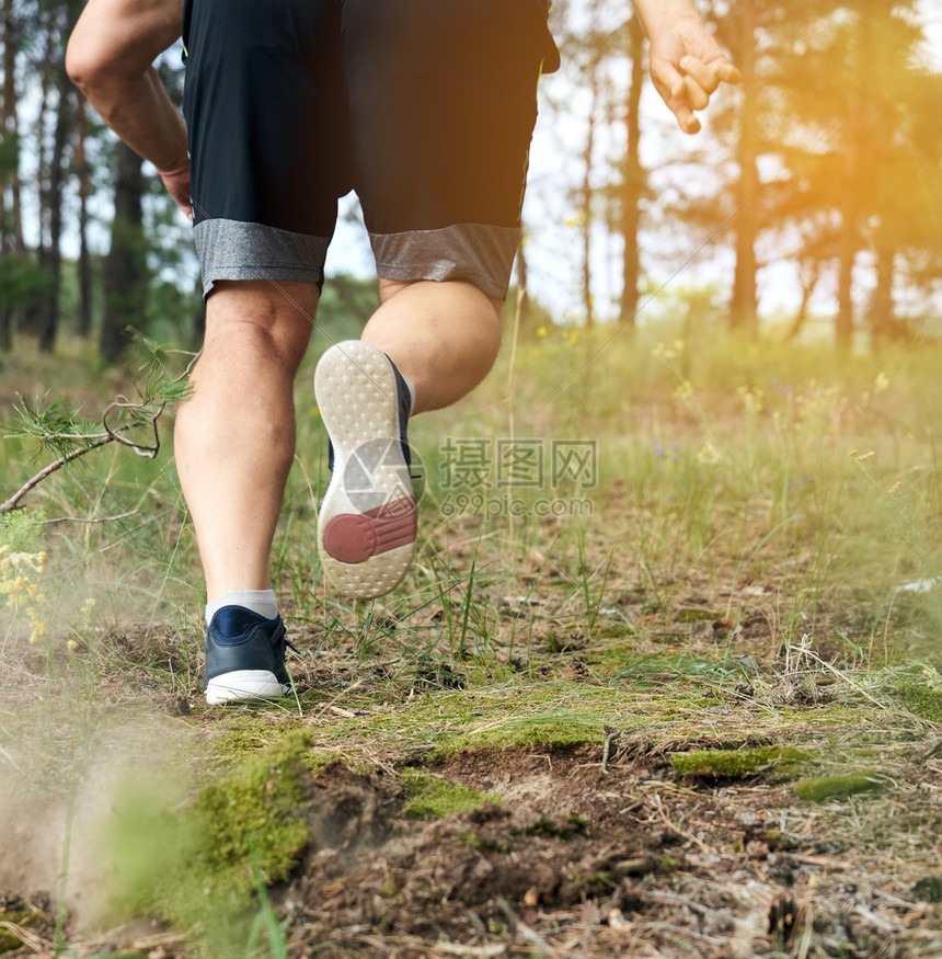 身穿黑短裤的成年男子奔跑在迷幻的森林中对抗明光的阳健康生活方式的概念和在新鲜空气中奔跑背视图片