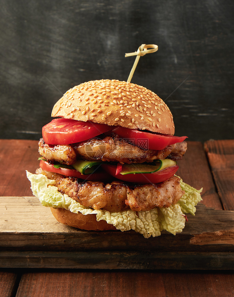 汉堡包加猪肉炒牛排红番茄新鲜圆包旧棕色木板上含芝麻种子图片