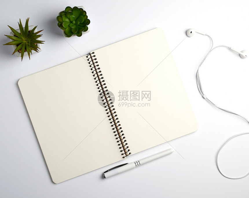 在锅白桌工作场所复制空间中用床单笔和绿色植物的螺旋笔记本图片