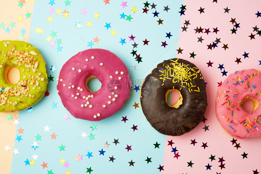 圆甜圈有各种填料和喷洒以抽象的颜色背景和节日装饰横幅图片