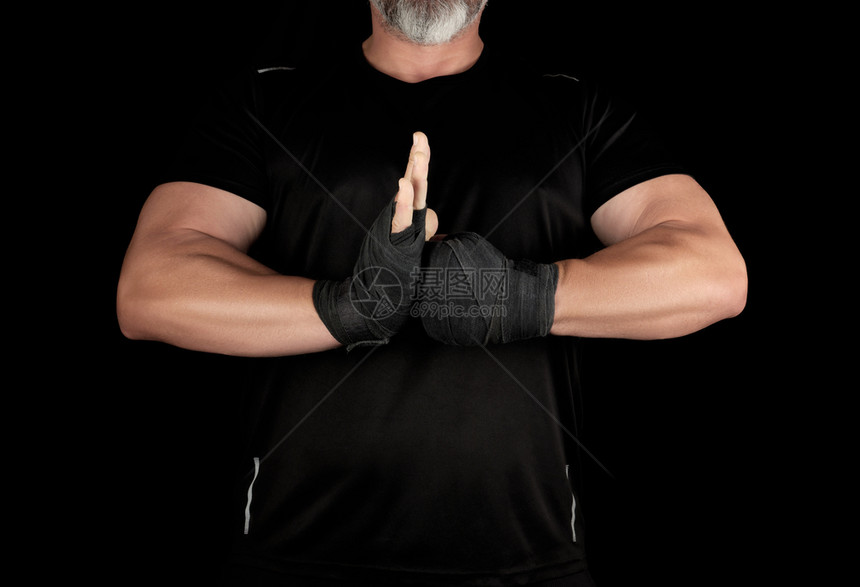 身着黑色衣服的成年肌肉运动员双手用黑色绷带和将双手放在胸前黑色背景手放在胸前图片