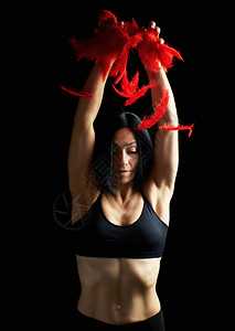 穿黑衣服的年轻运动女孩吐出红羽毛举起手臂低键图片