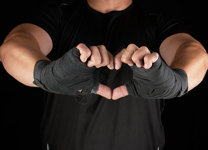 运动员显示心脏的符号男人手掌被包裹在黑色运动绷带里黑色背景运动绷带里图片
