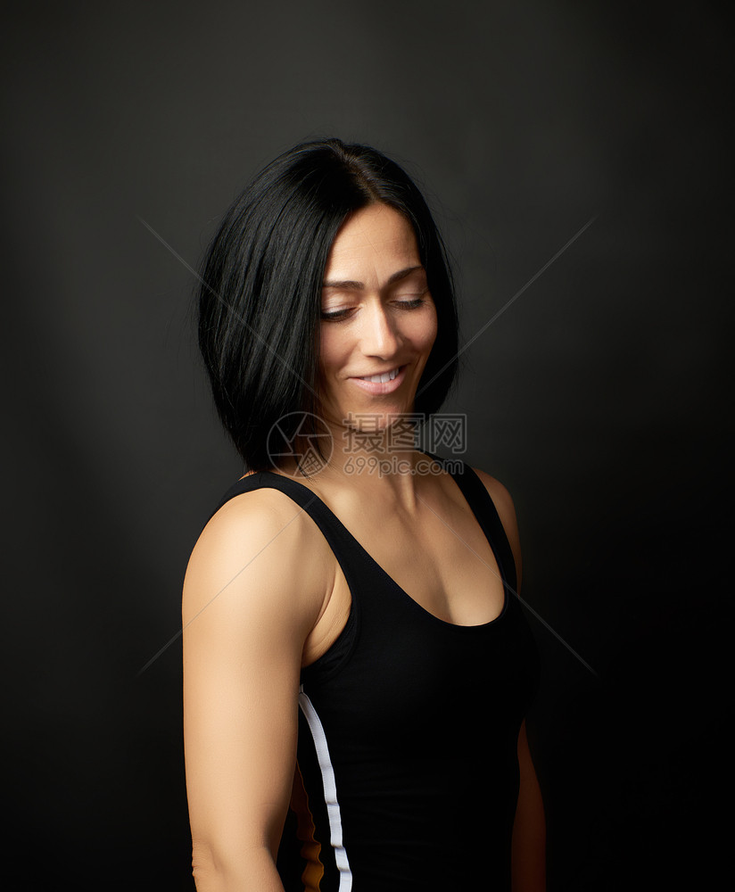 一位美丽的年轻女子肖像黑头发在暗背景上女孩笑着图片