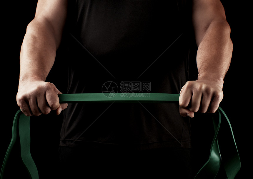 身穿黑色衣服肌肉身的运动员正在用绿色橡胶低键进行体操图片