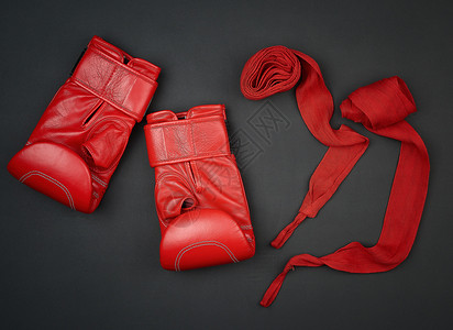 一对红色皮革拳击手套和黑底平的红色纺织品绷带图片