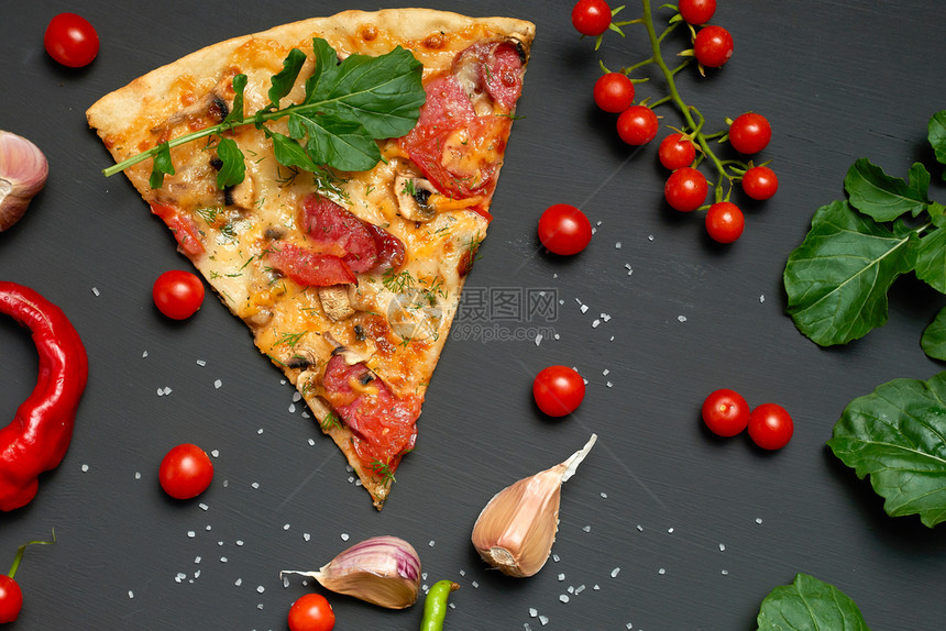 三角面包披萨片配蘑菇香肠西红柿和奶酪旁边是新鲜的青菜叶黑色背景平地图片
